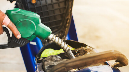 Green fuel dispenser refueling a motorcycle in a gas station.