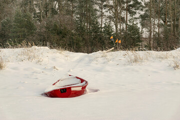 winter landscape from the seashore, red fisherman's boat on the seashore, sand and ice texture in the dunes