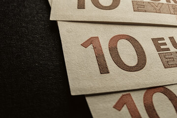 A set of ten euro bills on a black background. - 558183937
