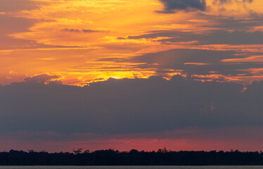 Obraz premium Amazing sunrise on the water of Amazon river in Brazil, nice soft warm light seeping through the clouds