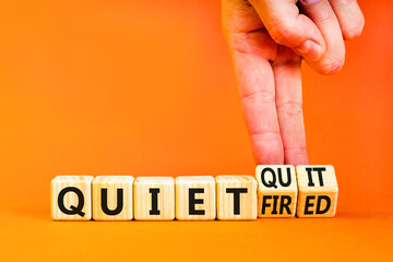 Quiet quit or fired symbol. Concept words Quiet quit and Quiet fired on wooden cubes. Businessman hand. Beautiful orange table orange background. Business quiet quit or fired concept. Copy space.