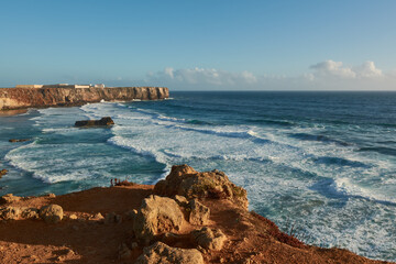 View of the beach Praia do Tonel with big waves and Sagres Fortress in the background. Algarve region, Portugal