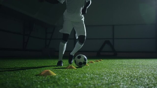 african football player training in hall, running with ball, kicking and dribbling, closeup view