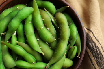 Bowl with green edamame beans in pods on table, top view