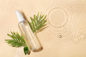 Fototapeta na wymiar Wet bottle of micellar water and green twigs on beige background, flat lay. Space for text