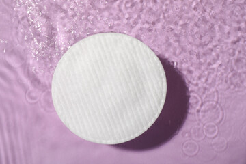 Cotton pad and micellar water on violet background, top view © New Africa