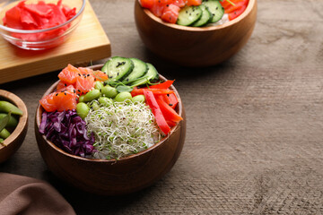 Delicious poke bowls with vegetables, fish and edamame beans on wooden table, space for text