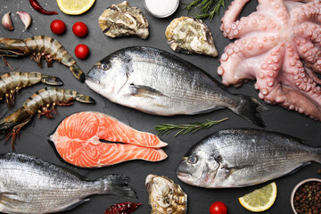 Flat lay composition with fresh raw dorado fish and different seafood on black table