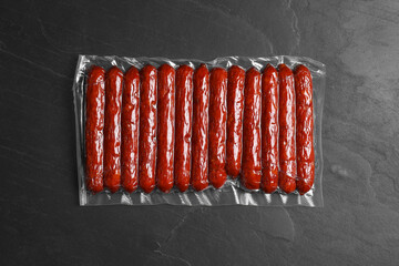 Vacuum pack of sausages on dark grey table, top view