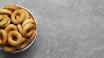 Bowl of tasty dry bagels (sushki) on grey table, top view. Space for text
