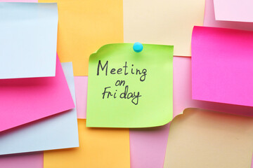 Paper with words Meeting on Friday pinned to pink background