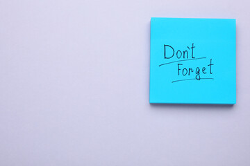 Paper note with phrase Don't Forget on light grey background, top view. Space for text
