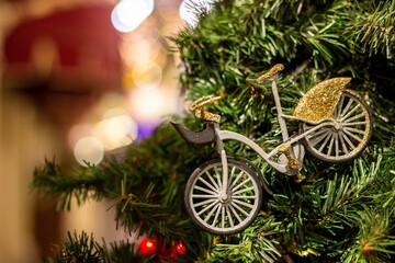 Christmas tree background and Christmas decorations in the mall. Toy gold bycicle on green fir. New Year theme
