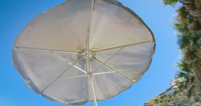 Dirty beach umbrella in wind from below