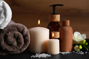 Fototapeta na wymiar Beautiful spa composition with different care products and burning candles on black table