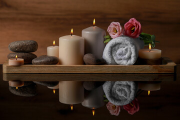 Obraz na płótnie Canvas Beautiful composition with spa stones, flowers and burning candles on mirror table against wooden background