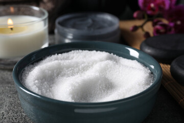 Beautiful composition with sea salt, burning candle, flowers and different spa products on grey table, closeup