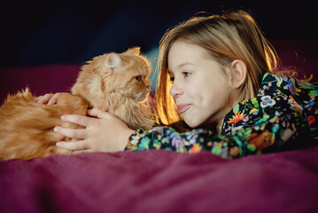 little child in bed with ginger cat