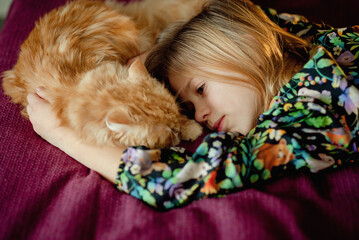 little child sleeping in bed with ginger cat