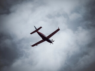 A single-engine turboprop airplane flaying against blue cloudy sky.