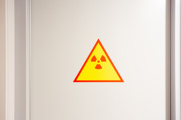 Red and yellow radiation precaution sign on the white steel wall.