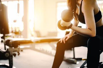 Fitness Asian Women in sportswear working out with weights over exercise bench exercising are...