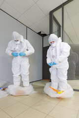 Operators in type 5/6 hazmat suits performing decontamination procedure, after asbestos incident,...