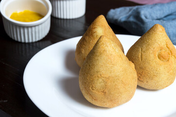 Three salty dumplings in the shape of a drop of the name coxinha, typical in Brazil