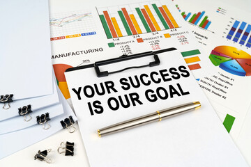 On the table among financial graphs and charts lies a tablet with the inscription - Your Success is Our Goal