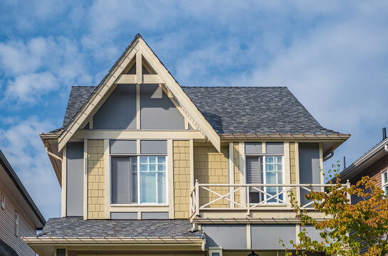 A perfect neighborhood. Houses in suburb in the north America. Top of a luxury house with nice windows over blue sky.