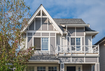 A perfect neighborhood. Houses in suburb in the north America. Top of a luxury house with nice windows over blue sky.