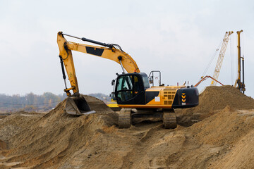 Yellow excavator is working on a sand embankment