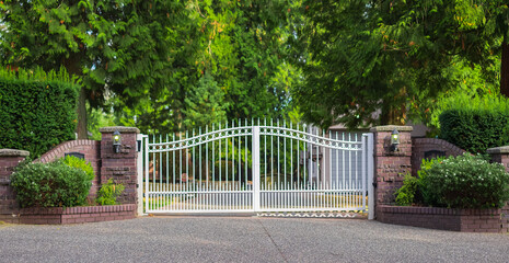 Double wrought-iron gate. Wrought iron gate and stone pillar. White wrought iron entrance gates to rural property - obrazy, fototapety, plakaty