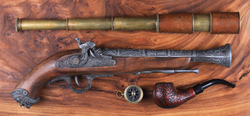 pirate pistol and spyglass on wooden background