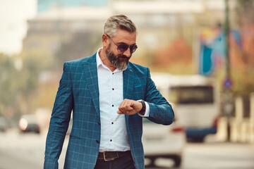 business, punctuality and people concept - senior businessman checking time on wristwatch or smart...