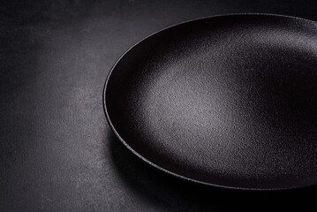 Empty beautiful black ceramic plate on a dark concrete background