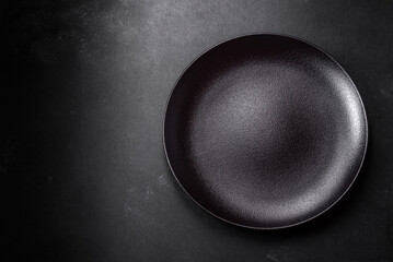 Empty beautiful black ceramic plate on a dark concrete background