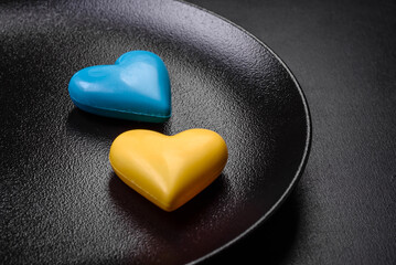 Chocolate hearts in the colors of the Ukrainian flag on a black ceramic plate