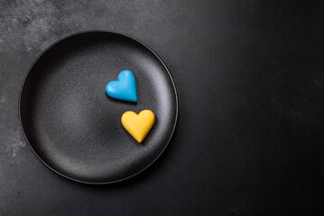 Chocolate hearts in the colors of the Ukrainian flag on a black ceramic plate