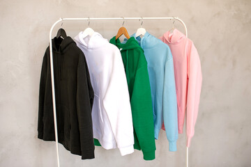 Hoodies of different colors hang on a hanger