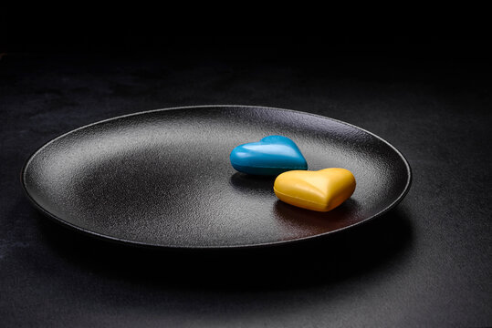 Chocolate hearts in the colors of the Ukrainian flag on a black ceramic plate - Powered by Adobe