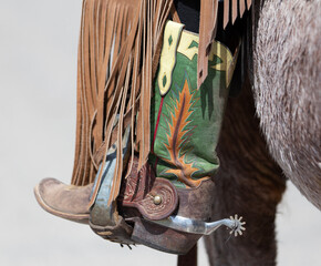 Green cowboy boot with spur in stirrup. - obrazy, fototapety, plakaty