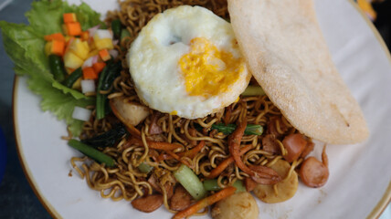 Asian authentic fried noodle with meat ball, veggie, shrimp crisp and egg in a plate.