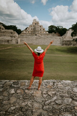 Travel woman in red dress looking at mayan ancient pyramid Etzná, Campeche, Mexico, Yucatán