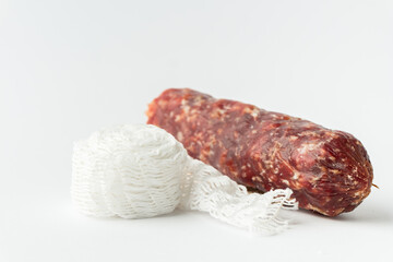 Sausage casing and cotton string roll for butchers. Elastic netting for roasting, boiling or smoking cold meat. Salami sausage on the white background.
