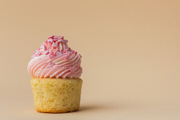 Close-up of vanilla cupcake with pink whipped butter cream top. Cream cheese frosting on muffin decorated with little pink heart shaped chocolate topping. Beige background. Happy Valentine's Day - obrazy, fototapety, plakaty