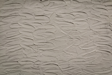 White wall or background of textured wavy stucco plaster material smeared onto surface creating a lovely design back and forth. Has shadows of black.