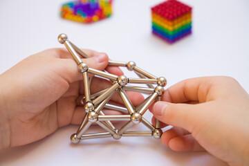 A child's hands hold a magnetic constructor toy.