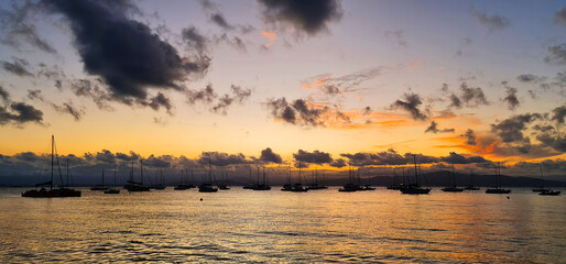 Fototapeta na wymiar Por do Sol com mar calmo e silhueta de barcos no horizonte