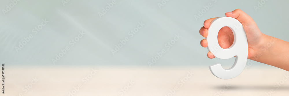 Aufkleber Number nine in hand. A hand holds a white number 9 on a blurred background. Concept with number nine. Birthday 9 years, percentage, ninth grade or day.